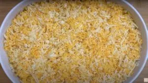 Close-up of shredded cheese blend in a white baking dish, ready for melting or cooking.